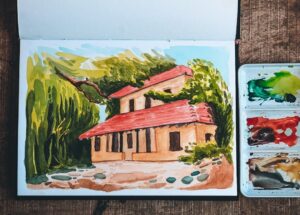 Aquarelle d’une maison de campagne dans un carnet de voyage, palette à côté