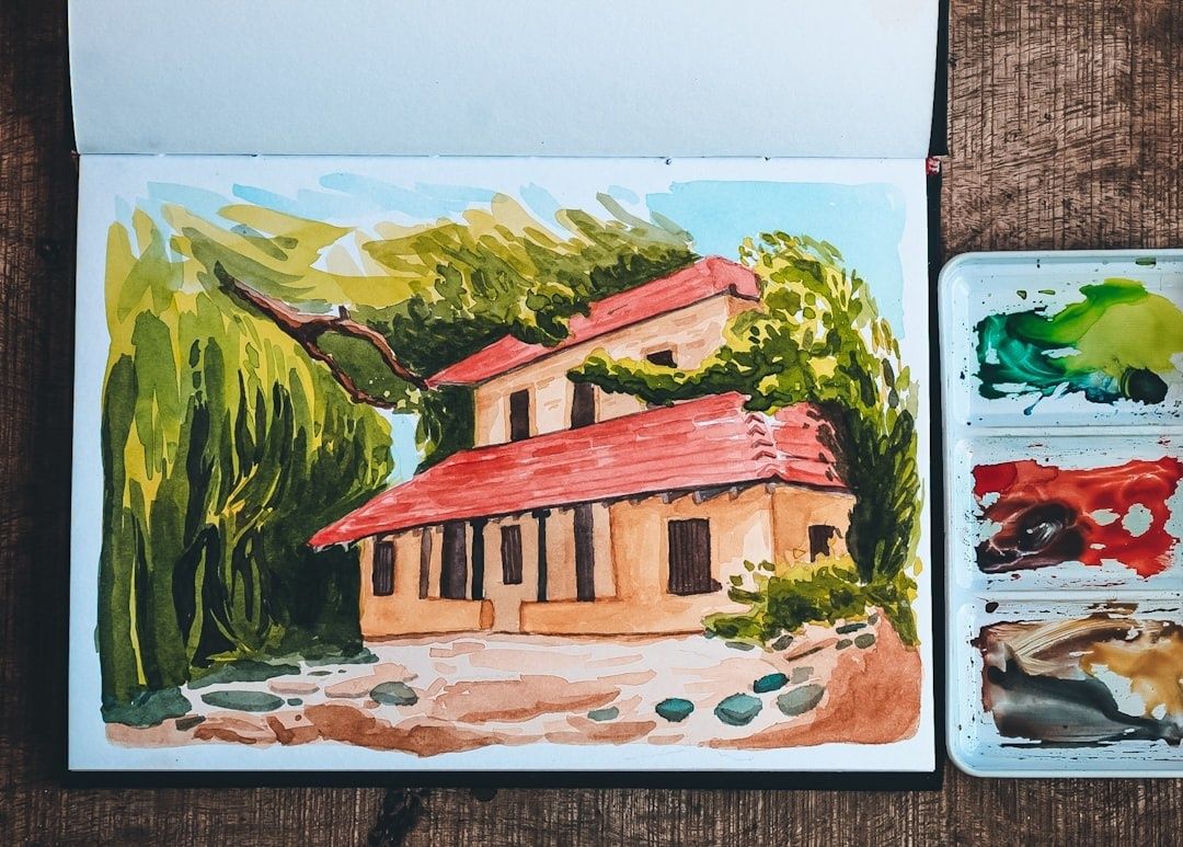 Aquarelle d’une maison de campagne dans un carnet de voyage, palette à côté