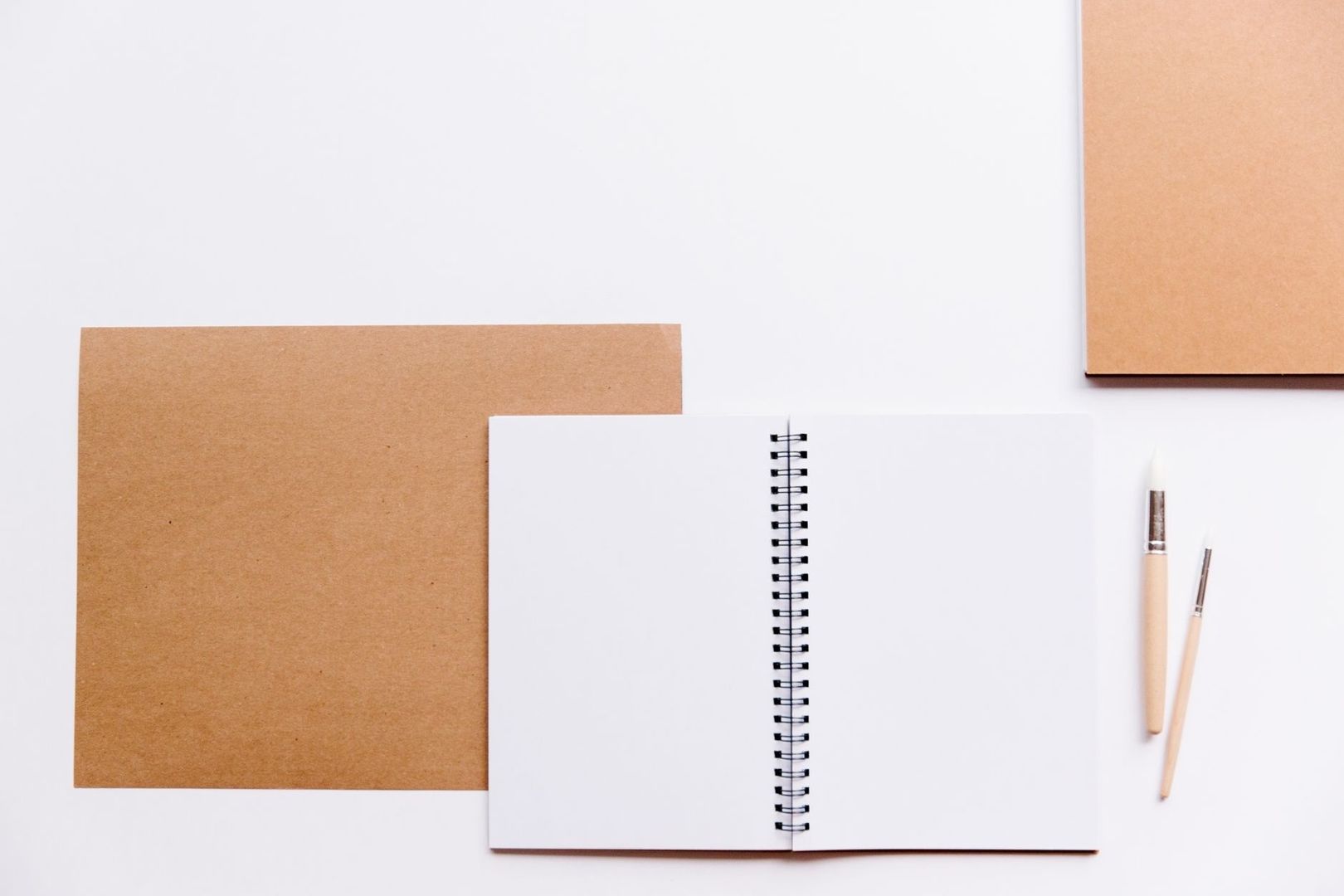 Carnet ouvert et crayons sur un bureau blanc, prêts à recueillir des souvenirs